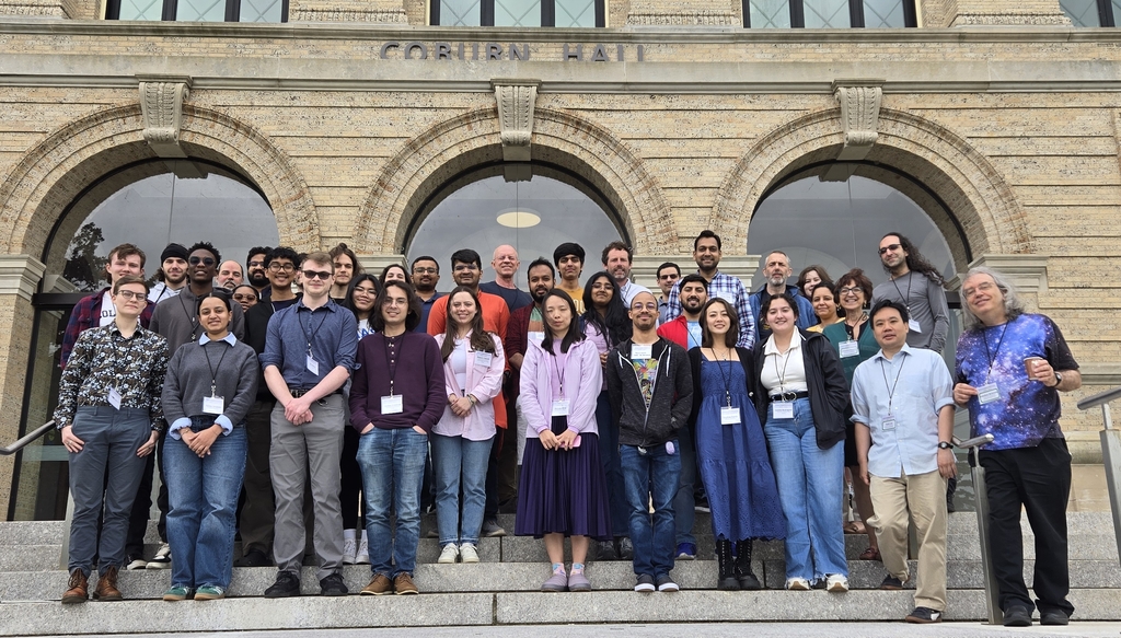 A group of about 40 people standing on steps in 4 rows outside a building with the words Corbon Hall